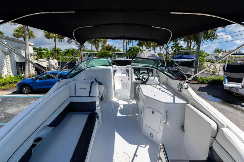 Slide: The Image of 2023 Hurricane SunDeck 2690 OB boat interior with seating and helm, parked outdoors. - 10