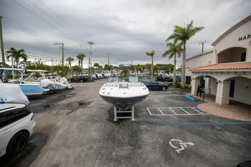 Slide: The Image of 2023 Hurricane SunDeck 2200 OB boat displayed at marina parking lot. - 13