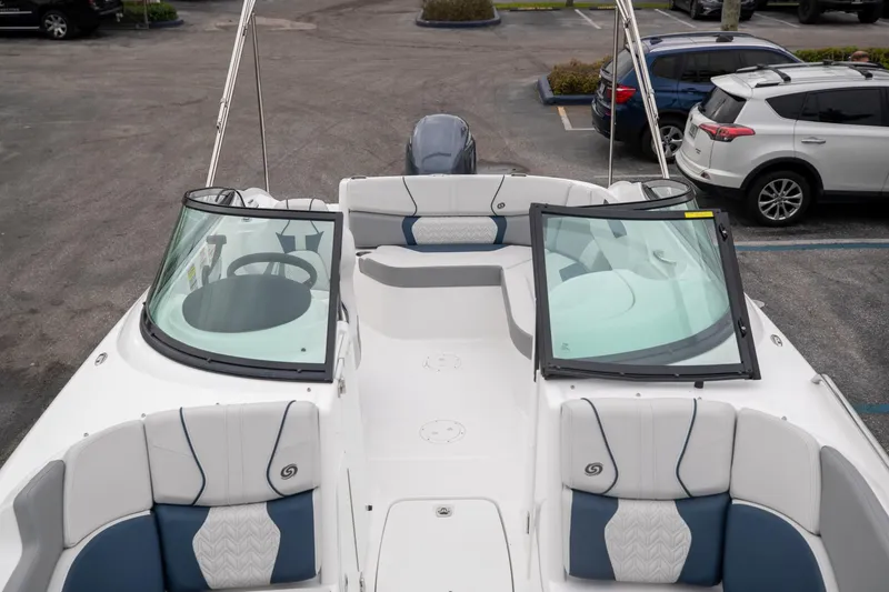Slide: The Image of 2023 Hurricane SunDeck 2200 OB boat interior with seating and windshield, parked in a lot. - 29