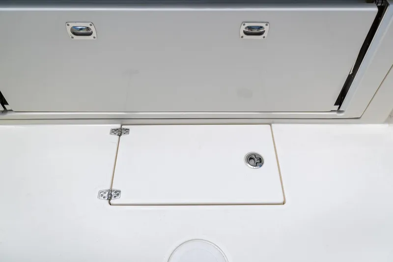 Slide: The Image of 2024 Cobia 320 CC boat storage compartment with secure latch and clean design. - 10