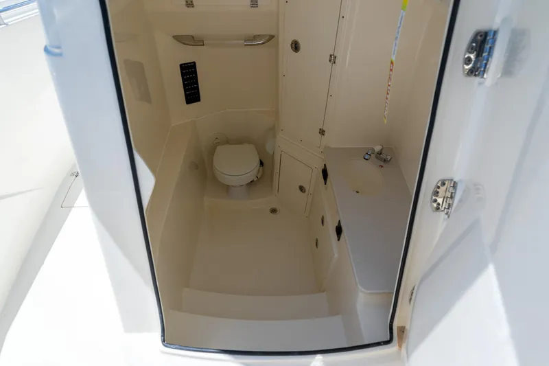 Slide: The Image of 2024 Cobia 320 CC boat interior with compact bathroom and toilet. - 42