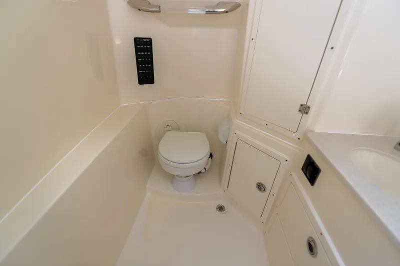 Slide: The Image of 2024 Cobia 320 CC boat bathroom with toilet, storage cabinets, and sink. - 43