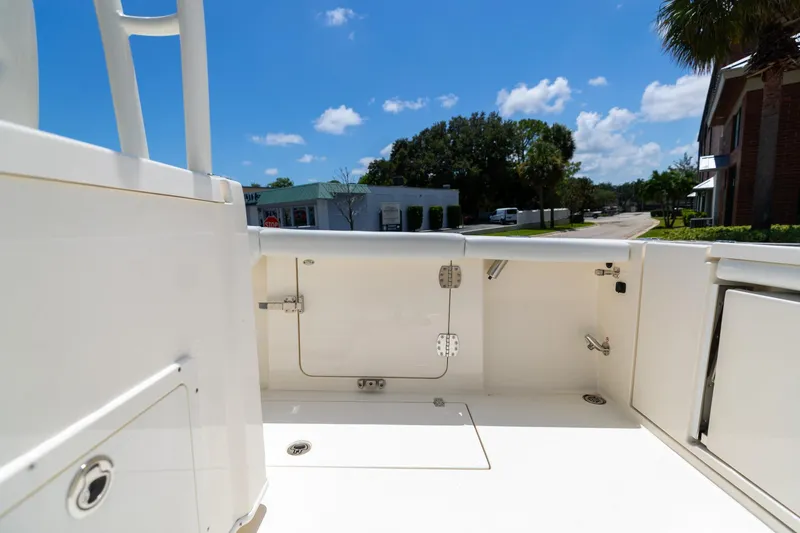Slide: The Image of 2024 Cobia 320 CC boat interior, showcasing storage compartments under a clear blue sky. - 12