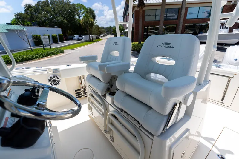 Slide: The Image of 2024 Cobia 320 CC boat interior with plush white seating and steering wheel. - 31