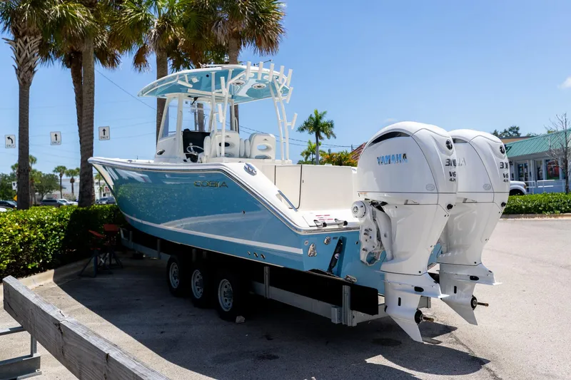 Slide: The Image of 2024 Cobia 320 CC boat with twin Yamaha engines on a trailer. - 4