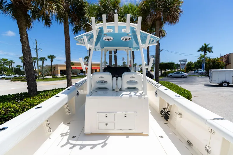 Slide: The Image of 2024 Cobia 320 CC boat with center console, parked outdoors under palm trees. - 7