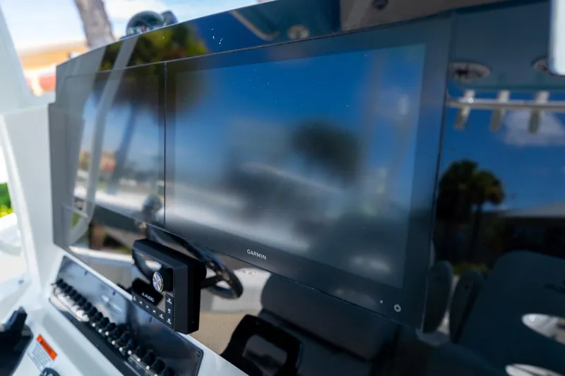 Slide: The Image of 2024 Cobia 320 CC boat dashboard with Garmin display and controls. - 24