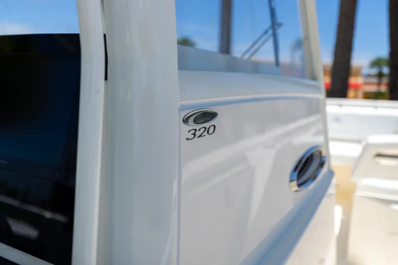 Slide: The Image of 2024 Cobia 320 CC boat detail with logo and sleek white finish. - 33