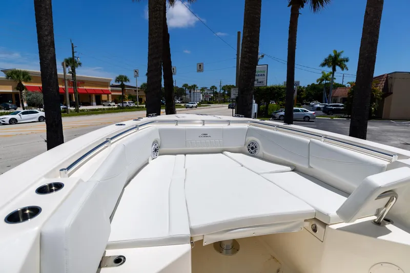 Slide: The Image of 2024 Cobia 320 CC boat with spacious white seating area, parked near palm trees. - 35