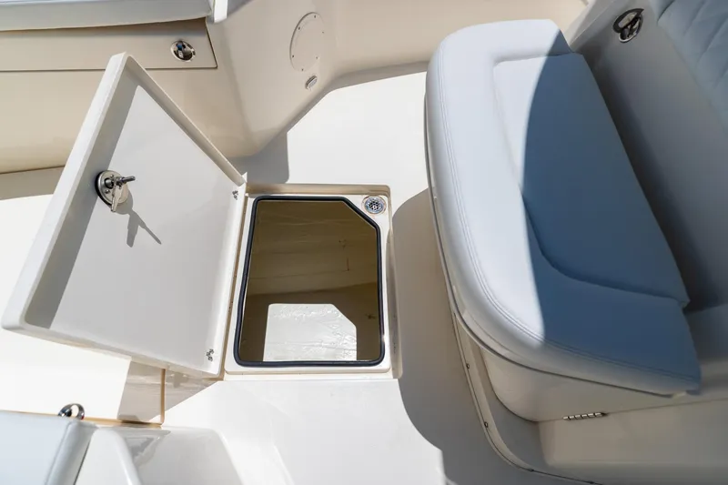 Slide: The Image of 2024 Cobia 320 CC boat storage compartment with open hatch and cushioned seating. - 38
