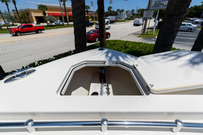 Slide: The Image of 2024 Cobia 320 CC boat deck with open storage compartment, street view in background. - 40