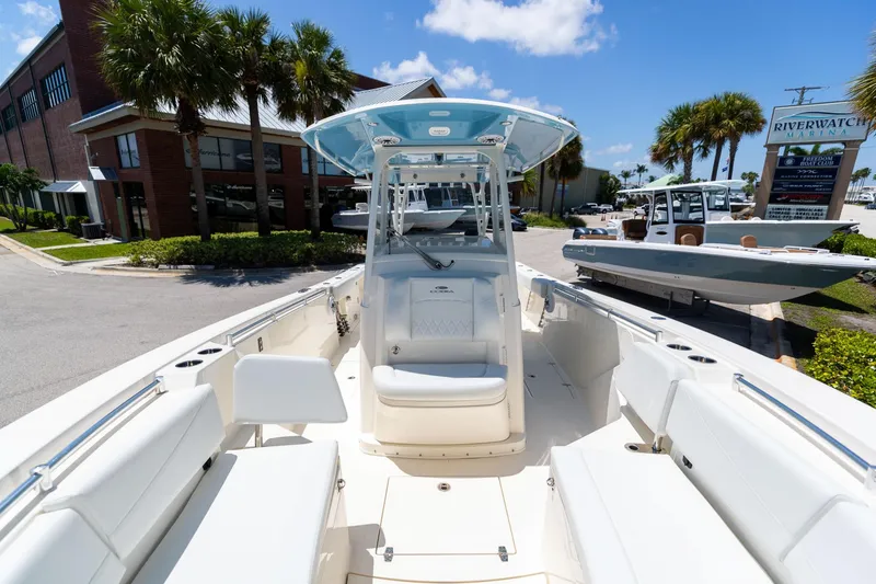 Slide: The Image of 2024 Cobia 320 CC boat with spacious seating, docked at a marina under a clear blue sky. - 41