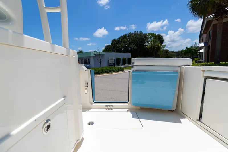 Slide: The Image of 2024 Cobia 320 CC boat interior with open door, blue storage, and sunny outdoor view. - 13