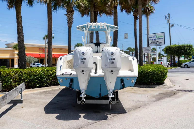 Slide: The Image of 2024 Cobia 320 CC boat with twin Yamaha engines, parked outdoors under palm trees. - 3