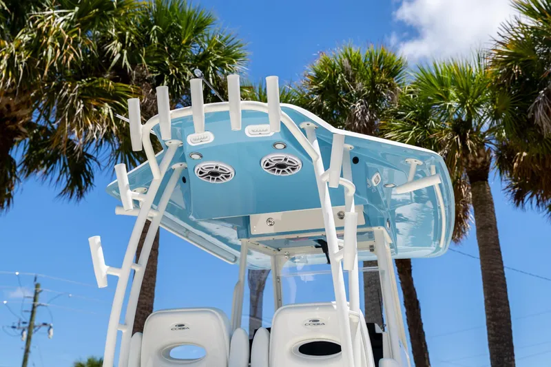 Slide: The Image of 2024 Cobia 320 CC boat with blue canopy and rod holders, set against palm trees. - 5