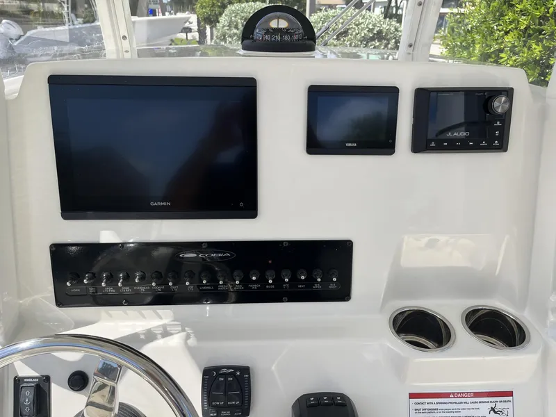 Slide: The Image of 2024 Cobia 240 CC boat dashboard with Garmin and Yamaha displays, JL Audio system. - 12