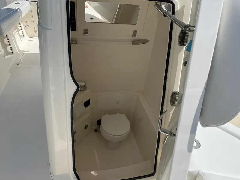 Slide: The Image of 2024 Cobia 240 CC boat interior with compact marine toilet. - 15