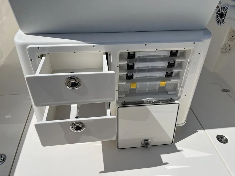 Slide: The Image of 2024 Cobia 240 CC boat storage compartments with open drawers and tackle boxes. - 26