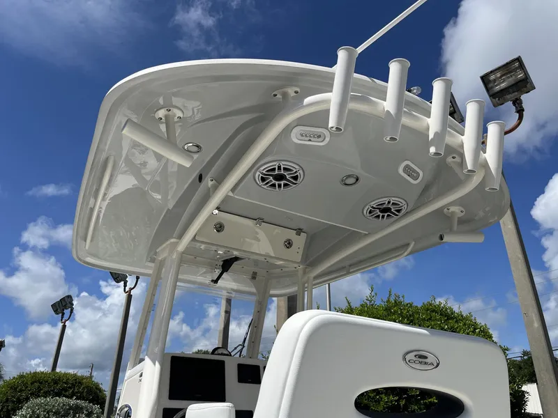 Slide: The Image of 2024 Cobia 240 CC boat with T-top and rod holders under a blue sky. - 28