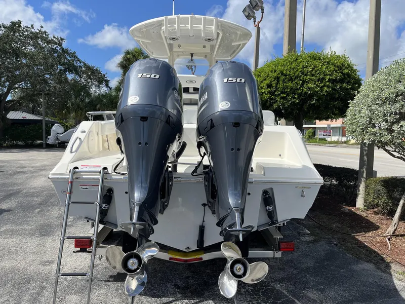Slide: The Image of 2024 Cobia 240 CC boat with dual Yamaha 150 engines, parked outdoors. - 5
