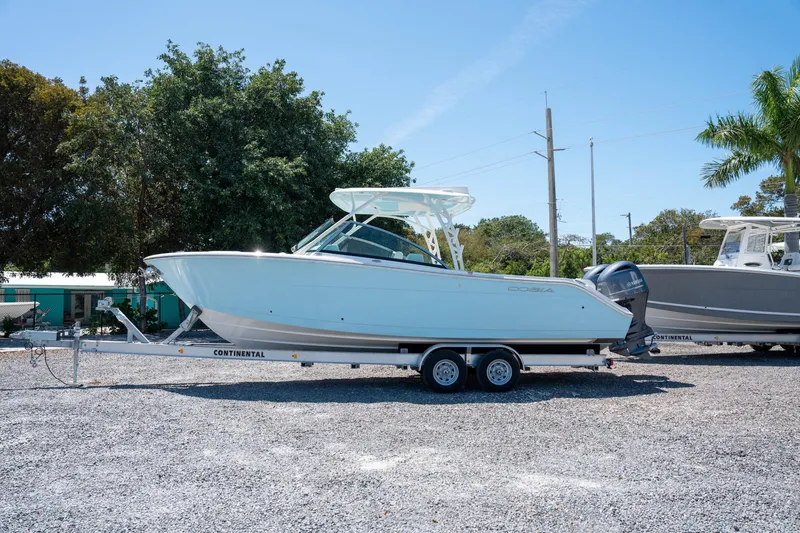 Slide: The Image of 2024 Cobia 280 DC boat on trailer, parked outdoors under clear sky. - 1
