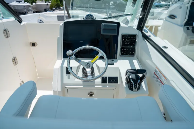 Slide: The Image of 2024 Cobia 280 DC boat helm with steering wheel and control panel. - 12