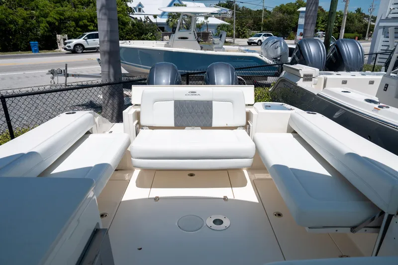Slide: The Image of 2024 Cobia 280 DC boat interior with white seating and dual outboard motors. - 14