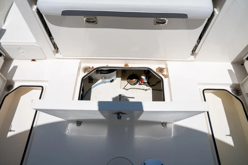 Slide: The Image of 2024 Cobia 280 DC boat storage compartment with open hatch, showcasing interior details. - 23