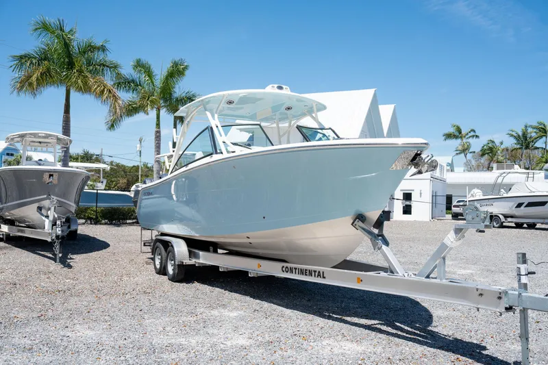 Slide: The Image of 2024 Cobia 280 DC boat on trailer, parked outdoors with palm trees. - 3