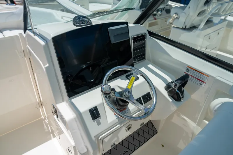 Slide: The Image of 2024 Cobia 280 DC boat helm with steering wheel and control panel. - 30