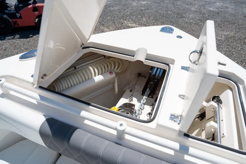 Slide: The Image of 2024 Cobia 280 DC boat storage compartment with open hatches and visible anchor chain. - 34