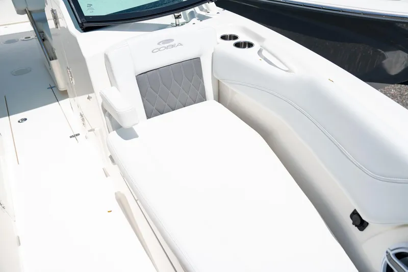 Slide: The Image of 2024 Cobia 280 DC boat interior with white cushioned seating and cup holders. - 38