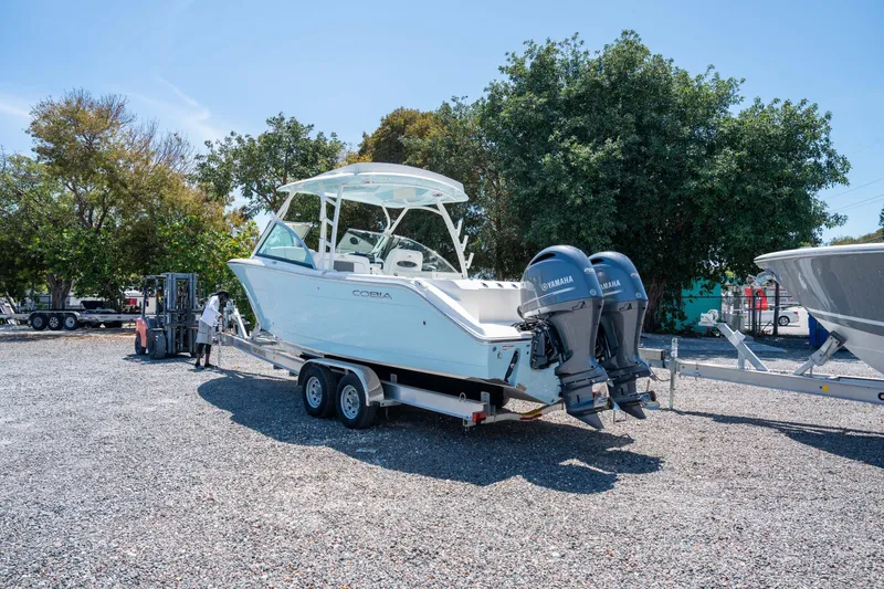 Slide: The Image of 2024 Cobia 280 DC boat on trailer with dual Yamaha engines, parked outdoors. - 7