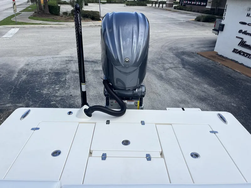 Slide: The Image of 2024 Hewes Redfisher 21 boat with outboard motor and Power-Pole, parked on pavement. - 19