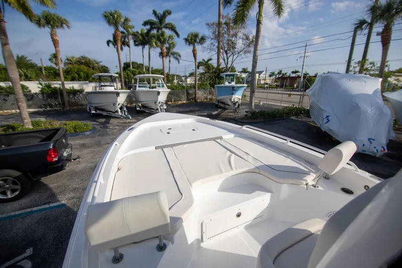 Slide: The Image of 2024 Sea Hunt BX 25 FS boat in a marina with palm trees and parked vehicles. - 17