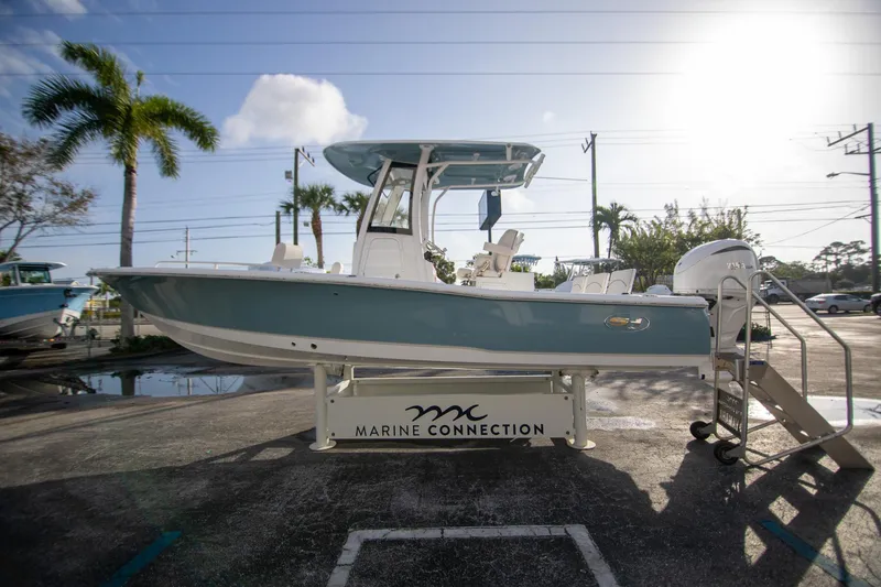 Slide: The Image of 2024 Sea Hunt BX 25 FS boat displayed outdoors on a stand, with palm trees in the background. - 3