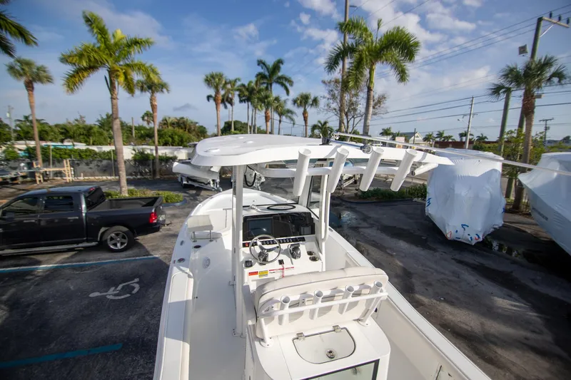 Slide: The Image of 2024 Sea Hunt BX 25 FS boat in a sunny marina with palm trees. - 7