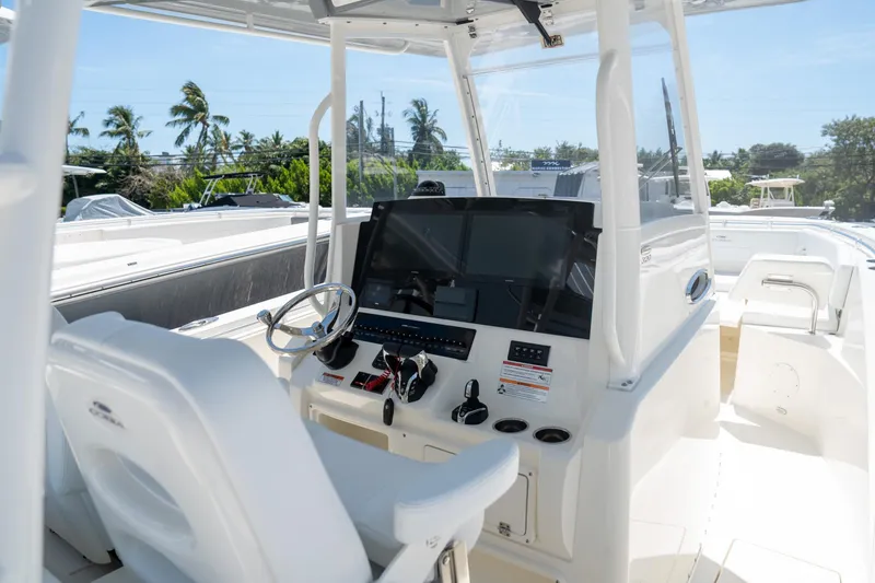 Slide: The Image of 2024 Cobia 320 CC boat cockpit with modern controls and steering wheel. - 10