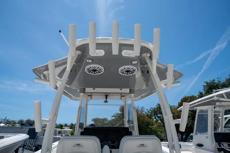 Slide: The Image of 2024 Cobia 320 CC boat with rod holders and speakers under a clear blue sky. - 28