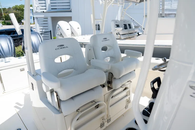 Slide: The Image of 2024 Cobia 320 CC boat interior with white cushioned seats and steering wheel. - 14