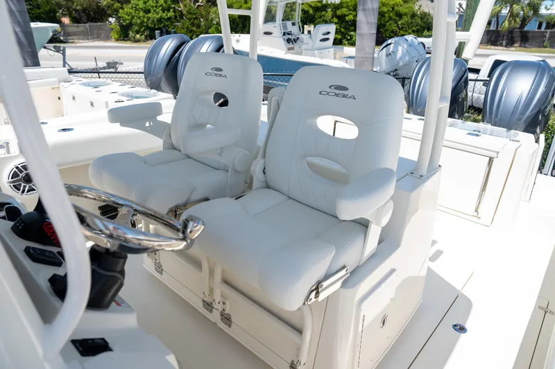 Slide: The Image of 2024 Cobia 320 CC boat interior with dual white captain's chairs and steering wheel. - 16
