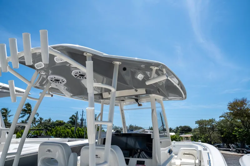 Slide: The Image of 2024 Cobia 320 CC boat with T-top and rod holders under clear blue sky. - 29