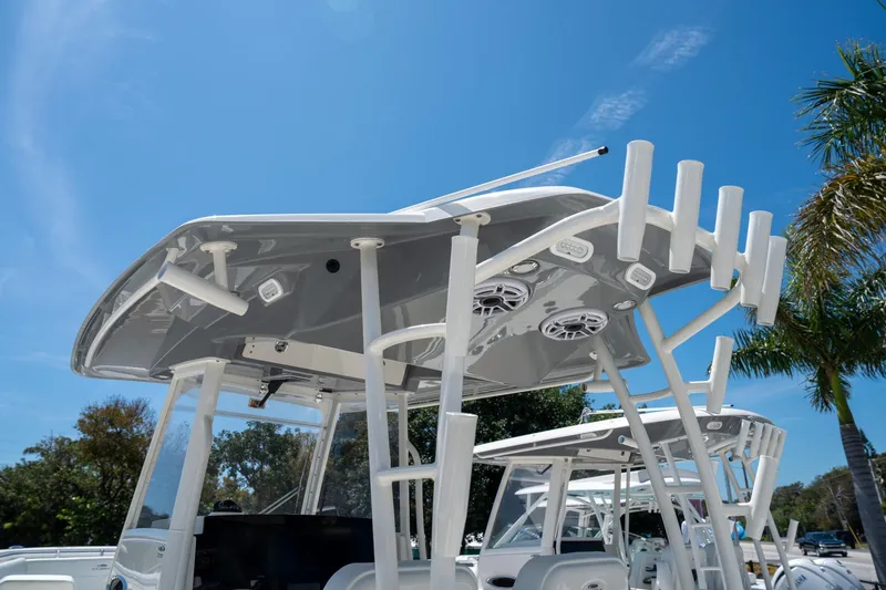 Slide: The Image of 2024 Cobia 320 CC boat with T-top and rod holders under a clear blue sky. - 30