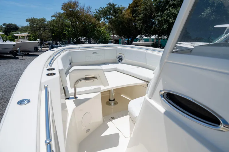 Slide: The Image of 2024 Cobia 320 CC boat interior with seating and table, surrounded by trees. - 36