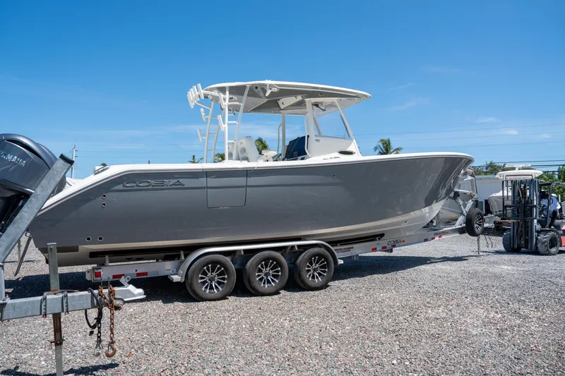 Slide: The Image of 2024 Cobia 320 CC boat on a trailer under clear blue sky. - 5