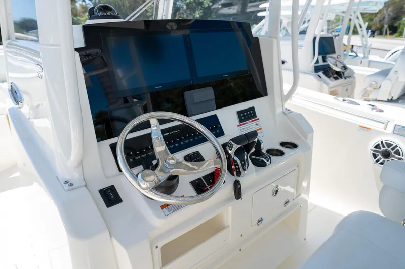 Slide: The Image of 2024 Cobia 320 CC boat dashboard with steering wheel and controls. - 12