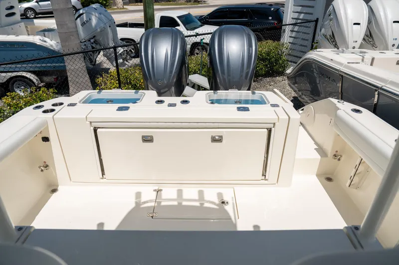 Slide: The Image of 2024 Cobia 320 CC boat deck with dual outboard engines and storage compartments. - 17