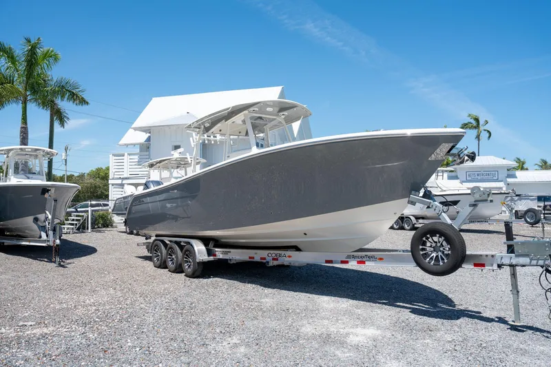 Slide: The Image of 2024 Cobia 320 CC boat on trailer, displayed outdoors under clear blue sky. - 3