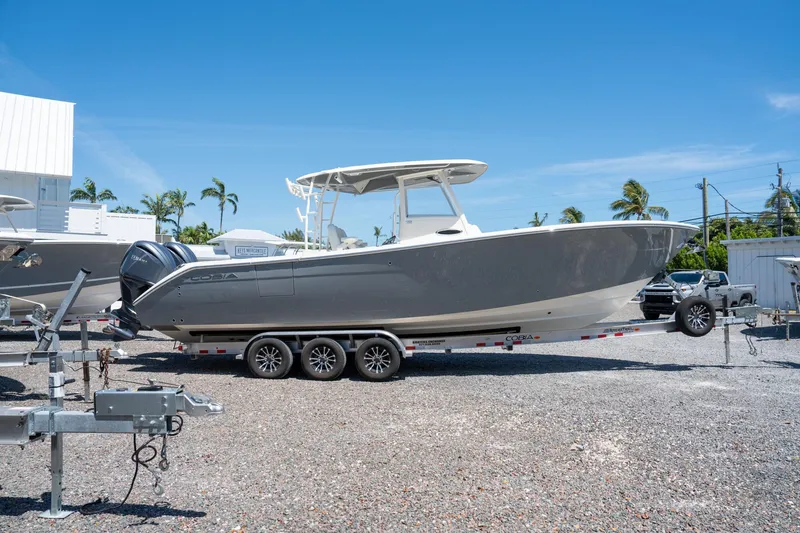 Slide: The Image of 2024 Cobia 320 CC boat on trailer, parked outdoors under clear blue sky. - 4