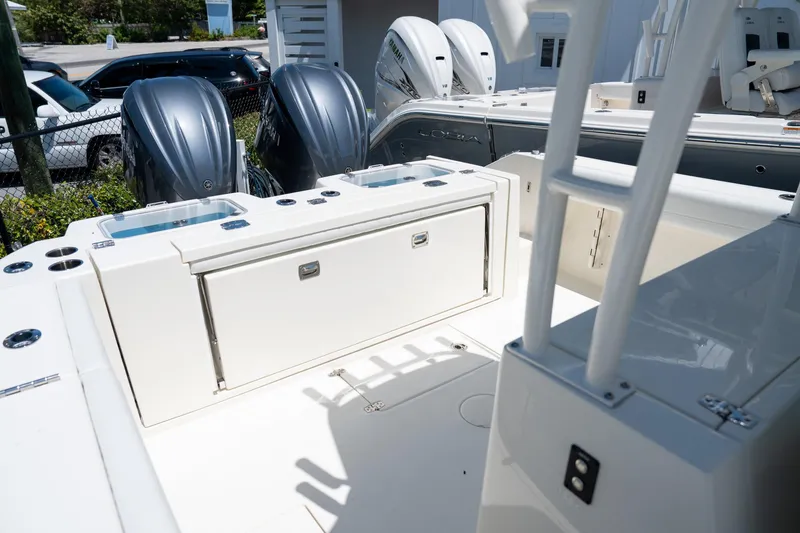 Slide: The Image of 2024 Cobia 320 CC boat deck with storage and dual outboard engines. - 19